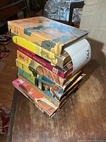 Stack of eight vintage hardcover books showing spines and wear