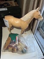 Horse figurine standing next to sealed bag of saddles and tack