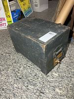 Side view of dark green wooden military crate showing metal handle and overall wear