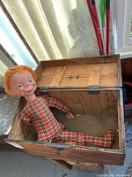 Doll lying inside open wooden trunk
