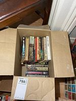 Open cardboard box showing vertical stack of war books and horizontal row of VHS cases