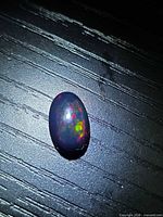 Top view of oval black opal showing multicolour flash