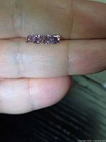 Four square octagon purple spinels on fingertip for scale