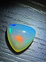 Top view of triangular cabochon opal showing orange and green play-of-color