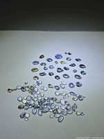 Group of loose Tanzanite stones spread on surface showing mix of faceted and cabochon cuts