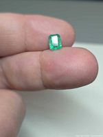 Emerald on fingertip showing face-up view