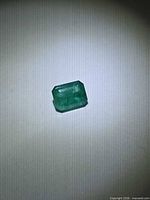 Loose octagon-cut emerald under spotlight