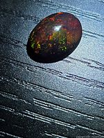 Front view of oval Ethiopian black opal showing multicolour pinfire play-of-colour