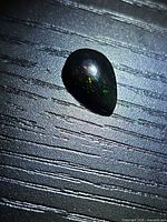 Top view of pear cabochon black opal showing play of color