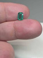 Emerald on fingertip showing octagon shape and colour