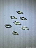 Seven marquise cut pale yellow-green gemstones on white background