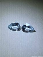 Two light blue pear-cut gemstones side by side on white background