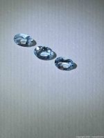 Three light blue oval-cut gemstones on neutral background