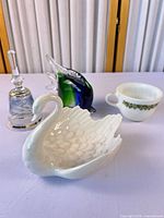 Group shot showing all four items: glass bell, art glass fish, ceramic swan, Pyrex cup