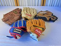 Group of five gloves showing brands and overall condition
