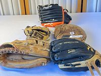 Four gloves laid out showing different brands and colors