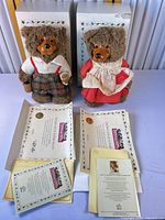 Both bears, certificates, paperwork, and boxes displayed
