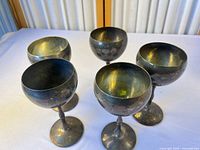 Five silver-plated goblets grouped on table