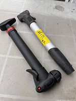 Both bicycle hand pumps side by side on floor for size, color, design and wear reference