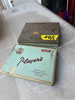 Top view of both cigarette tins showing branding and wear