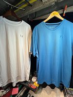 White and blue Under Armour t-shirts hanging