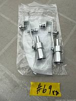 Two silver aluminum turbo sound whistle simulators in clear plastic bag with mounting hardware