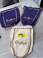 Two purple and one beige Crown Royal pouches displayed flat on surface
