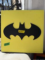 Front view of square Batman wall art showing black bat logo on yellow background