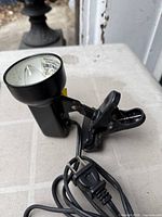 Side view of black clip-on lamp showing clamp mechanism and lamp head