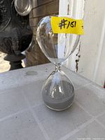 Full view of clear glass hourglass timer with gray sand
