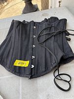 Front view of black corset showing metal busk and boning