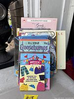 Front view of stacked books showing Beauty and the Beast activity book, Goosebumps, Hello Kitty and others