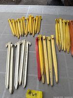 Grouped yellow, white, red, orange plastic tent pegs laid out on table