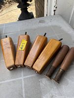 All six vintage wooden furniture legs: four tapered block style, two turned conical with brass ferrules