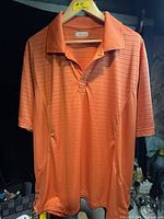 Front view of orange polo shirt on hanger