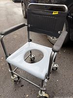 Overall view of commode chair showing frame, seat, casters