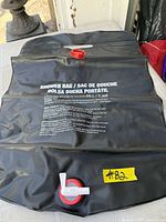Black 20 L shower bag showing red fill cap, white spigot and printed instructions