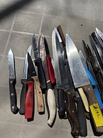 Cluster of assorted kitchen knives showing variety of blade sizes and handle colours