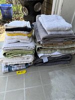 Two stacked piles of assorted towels displayed on tiled surface