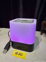 Night light illuminated purple, showing cube shape, USB cable, black base