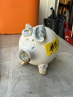 Front and side view of white ceramic piggy bank with blue accents