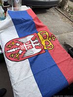 Full view of Serbian flag laid flat showing crest and tricolour stripes