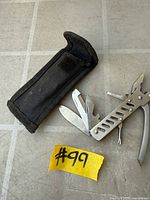 multitool open with several implements extended alongside belt sheath