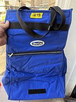 Front view of blue StayzCold cooler bag showing zip pocket and strap