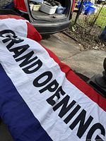 Full view of red, white and blue GRAND OPENING banner on ground