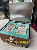 Open tin showing two card decks seated in teal tray