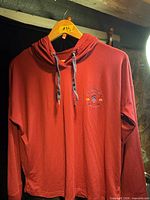 Full front view of red hooded pullover on hanger
