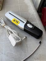 Handheld VTech shredder with power adapter and wrist strap