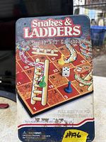 Front of metal tin showing Snakes & Ladders artwork, size indication and included pieces