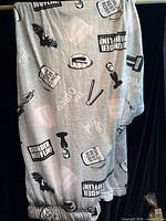 Full view of grey The Office printed lounge pants hanging to show design and length
